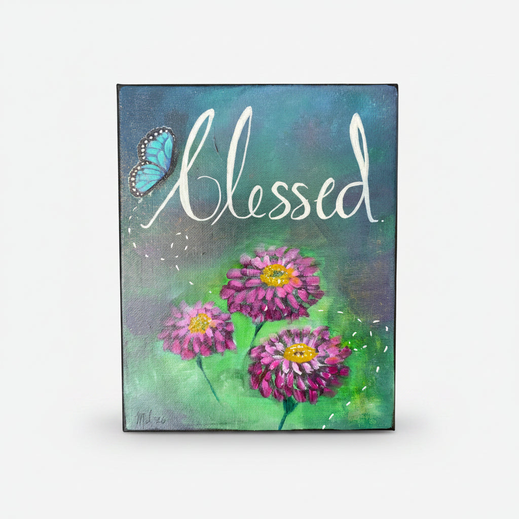 A rectangular canvas painting featuring the word 'Blessed' in white script over a blue and green painted background, with three pink-purple zinnia flowers and a blue butterfly.
