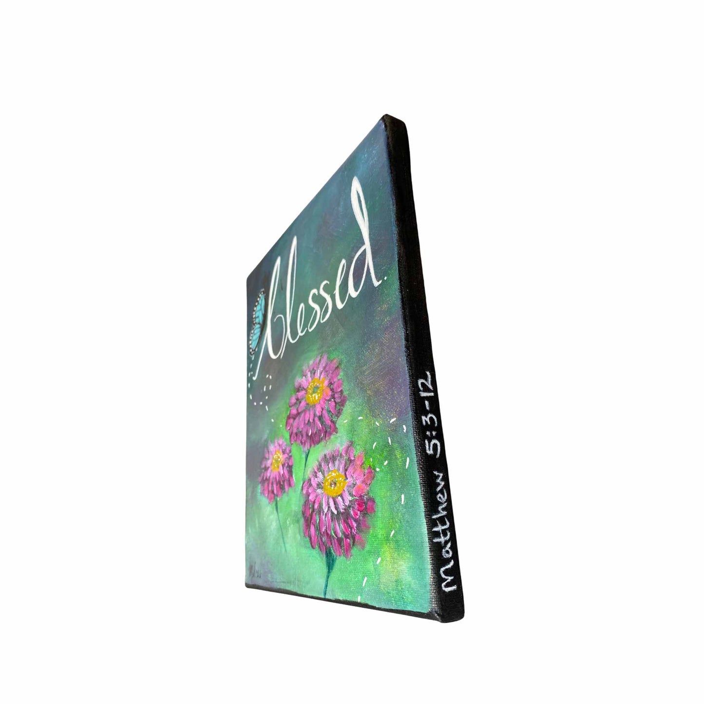 An 11x14" canvas painting shown at an angle, featuring three pink and purple zinnia flowers with yellow centers on a green and teal textured background. The word 'Blessed' is written in white script across the top, and 'Matthew 5:3-12' is written vertically on the side edge.