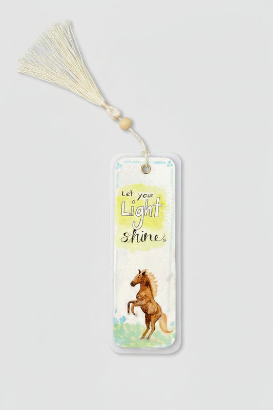 A rectangular laminated watercolor bookmark with a cream tassel and wooden bead, featuring the text 'Let your Light Shine' and an illustration of a brown horse.