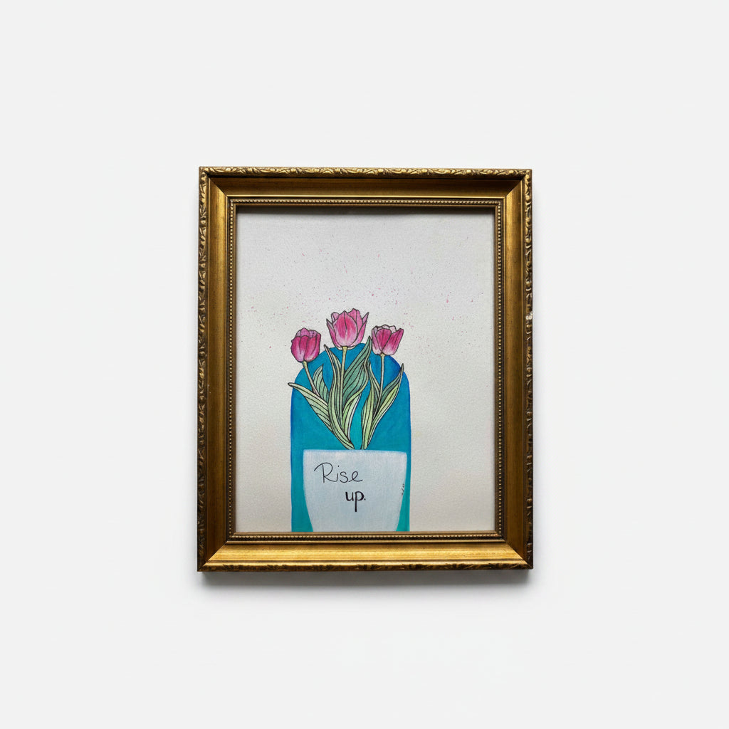 A framed art print featuring a white vase with pink tulips and the handwritten text 'Rise up' with a boho teal background, enclosed in an ornate gold frame.
