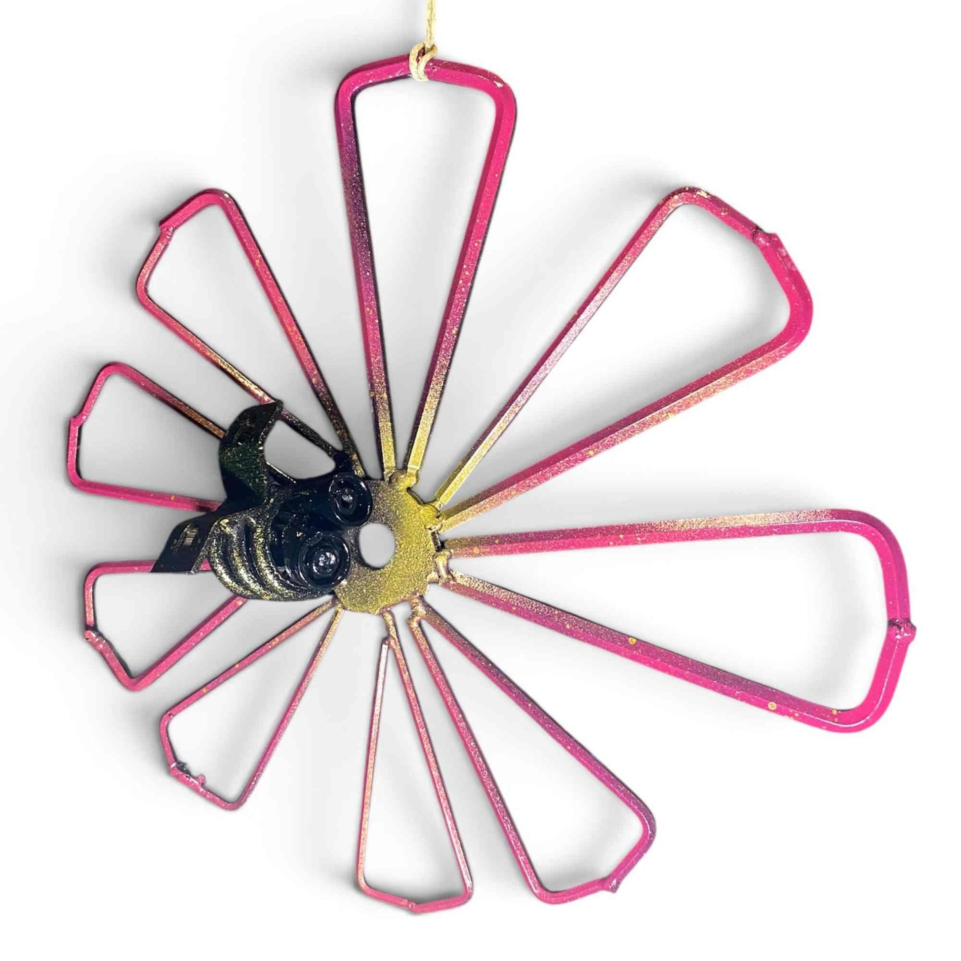 A metal flower wall decoration with a scrap metal bumble bee with illustrative eyes or goggles on it's face.